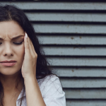 New Trial Shows Cefaly is a Safe and Effective Preventive Treatment for Chronic Migraine a woman in pain is holding her head with her eyes closed