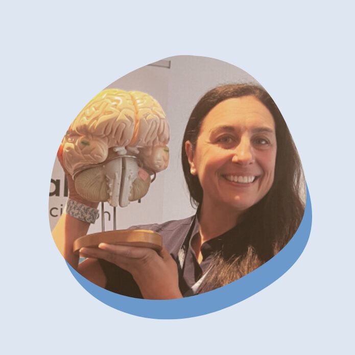 A woman smiles while holding a model of the brain